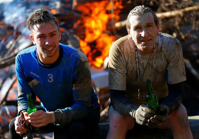 Competitors relax in front of a fire after finishing the Wildsau Dirt Run (Wild Boar Dirt Run) obstacle course fun race at Hellsklamm ravine in Obertriesting, Austria, October 22, 2016. (Photo by Heinz-Peter Bader/Reuters)