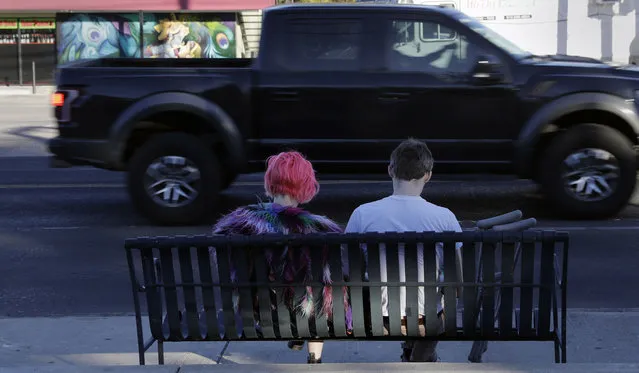 A couple wait at a bus stop, Tuesday, March 20, 2018, in Austin, Texas, a city that has seen five bombings that have killed two people and badly wounded four others since March 2. The recent blasts have sent a deep chill through a hipster city known for warm weather, live music, barbeque and, above all, not taking itself too seriously. (Photo by Eric Gay/AP Photo)