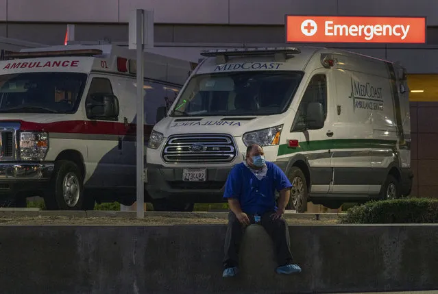 Darren Arthur, an environmental services worker, takes a break outside the Los Angeles County+USC Medical Center emergency ramp in Los Angeles, late Wednesday, December 16, 2020. The state has been grappling with soaring cases and hospitalizations. Hospitals are filling up so fast that officials are rolling out mobile field facilities and scrambling to hire more doctors and nurses. (Photo by Damian Dovarganes/AP Photo)