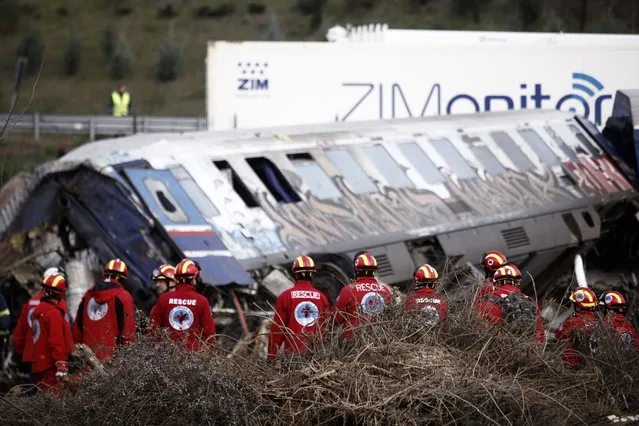 Rescuers stand near debris of trains after a collision in Tempe, about 376 kilometres (235 miles) north of Athens, near Larissa city, Greece, Wednesday, March 1, 2023. Rescuers searched Wednesday through the burned-out wreckage of two trains that slammed into each other in northern Greece, killing and injured dozens of passengers. (Photo by Giannis Papanikos/AP Photo)