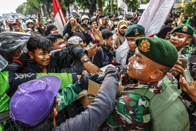 Military personnel distribute free food for the protesters during a protest outside the Mobile Brigade police headquarters in Jakarta, Indonesia, 30 August 2025. Government buildings and police vehicles were set on fire on during overnight protests across the country following the death of a motorbike hailing driver during an earlier protest against the housing allowance for members of parliament. (Photo by Mast Irham/EPA)