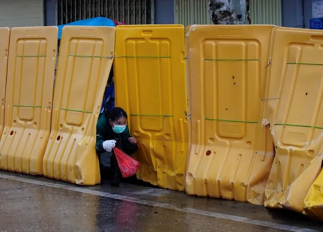 A woman wearing a face mask gets out through barriers, which have been built to block buildings from a street in Wuhan, Hubei province, the epicenter of China's coronavirus disease (COVID-19) outbreak, March 29, 2020. (Photo by Aly Song/Reuters)