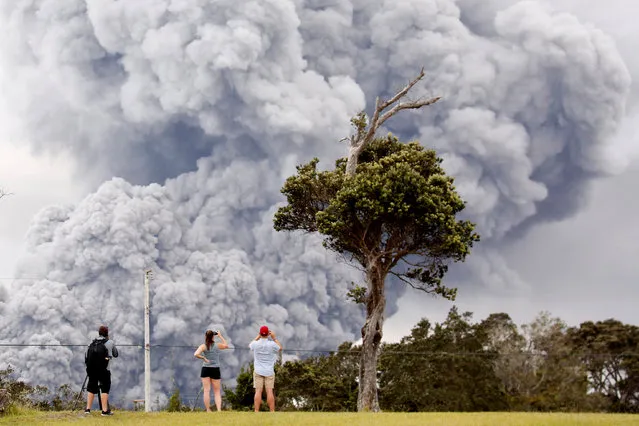 People watch as ash erupts from the Halemaumau crater near the community of Volcano during ongoing eruptions of the Kilauea Volcano in Hawaii on May 16, 2018. (Photo by Terray Sylvester/Reuters)
