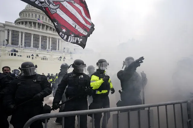 Police hold off Trump supporters who tried to break through a police barrier, Wednesday, January 6, 2021, at the Capitol in Washington. As Congress prepares to affirm President-elect Joe Biden's victory, thousands of people have gathered to show their support for President Donald Trump and his claims of election fraud. (Photo by Julio Cortez/AP Photo)