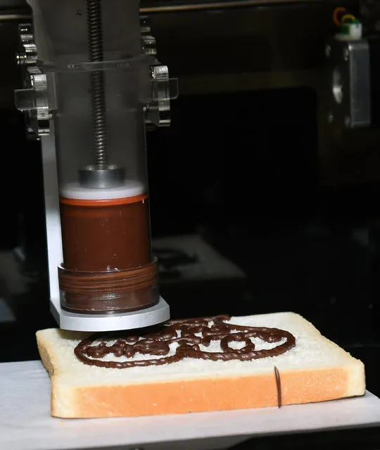 An XYZprinting 3D Food Printer is shown putting a chocolate cookie design on a piece of bread for a demonstration during a press event at the Mandalay Bay Convention Center for the 2015 International CES on January 4, 2015 in Las Vegas, Nevada. Users can upload any design or import them from the Internet to use in making cookies and cake decorations. (Photo by Ethan Miller/Getty Images)