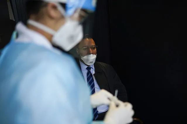 A medical worker, wearing a full protective gear, takes a nose swab from a traveller who arrived from U.K., to be tested for COVID-19 in a Red Cross test center at Gare du Midi international train station in Brussels, Tuesday, January 19, 2021. Belgium is strengthening its rules for travellers entering the country by train or bus in a bid to limit the spread of a more contagious variant of the coronavirus detected in Britain. (Photo by Francisco Seco/AP Photo)
