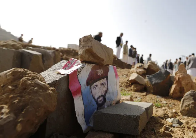 A poster with an image of a soldier lies on his grave after he was killed by al Qaeda militants in the Wadi Hadramout region in northeastern Yemen, at a military cemetery in Sanaa August 10, 2014. (Photo by Khaled Abdullah/Reuters)