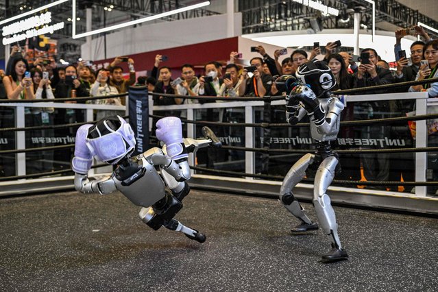 Remote-controlled robots by Unitree Robotics take part in a boxing match at the Unitree Robotics stand during the 8th International Import Expo (CIIE) in Shanghai on November 6, 2025. (Photo by Hector Retamal/AFP Photo)
