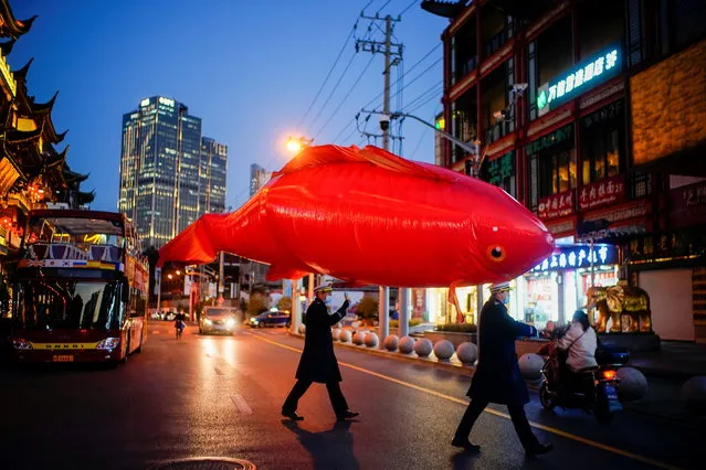 Security guards wearing face masks carry a giant balloon in the shape of a fish ahead of the Chinese Lunar New Year festivity at Yu Garden, following the coronavirus disease (COVID-19) outbreak in Shanghai, China on January 29, 2021. (Photo by Aly Song/Reuters)