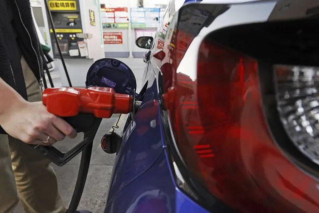 A person fills petrol at a fuel station in Tokyo on March 16, 2022. Japan racked up a trade deficit in April, marking the 21st month in a row of deficits, although it declined dramatically compared to a year ago, as exports recovered, according to government data released Thursday, May 18, 2023. (Photo by Kyodo News via AP Photo)