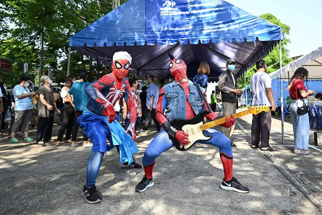 Two men dressed as Spiderman to encourage people voting perform in front of a queue of voters waiting to cast their ballot at a polling station during Thailand's general election in Bangkok on May 14, 2023. (Photo by Manan Vatsyayana/AFP Photo)