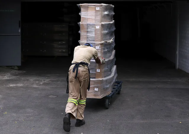 A worker unload coffins from a delivery truck for sale at AVBOB's funeral parlour in Bellville, Cape Town, South Africa, Saturday, January 30, 2021. The COVID-19 pandemic has claimed the lives of more than 10,000 people in the Western Cape Province with burial space running out in the inner city and crematoriums running six days a week out of curfew hours to keep up with the demand. (Photo by Nardus Engelbrecht/AP Photo)