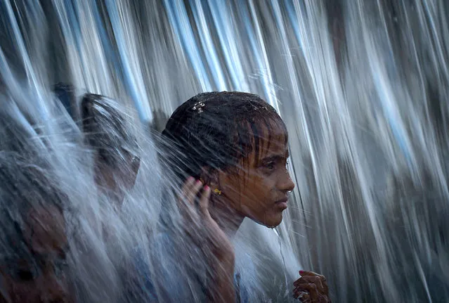 A girl plays with a curtain of water at Madureira park in Rio de Janeiro, Brazil, on January 25, 2014. (Photo by Yasuyoshi Chiba/AFP Photo)
