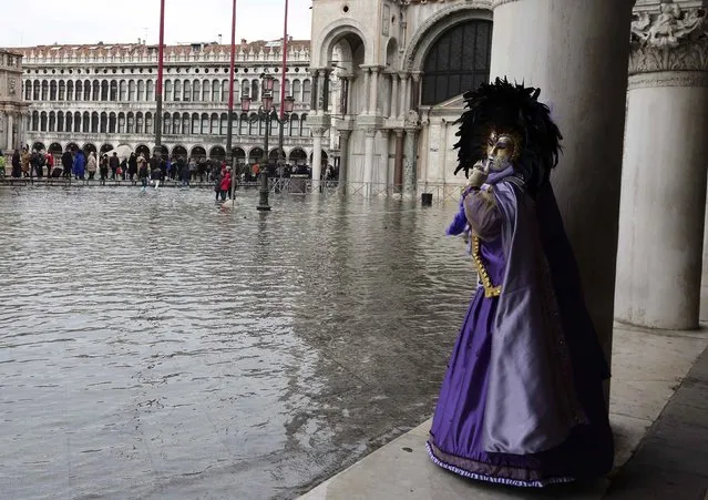 A masked reveller poses along the flooded St. Mark's Square during a period of seasonal high water and on the first day of carnival, in Venice February 1, 2015. (Photo by Stefano Rellandini/Reuters)