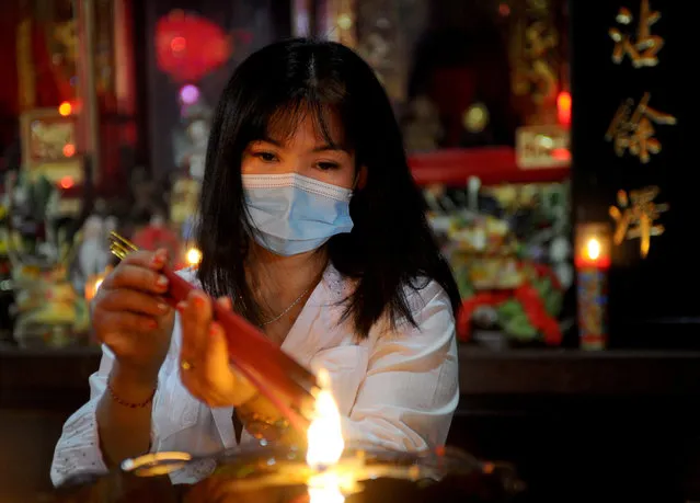 A woman burns incense sticks to pray at a Chinese temple on the first day of the Lunar New Year in Kuta, on Indonesia's resort of Bali on February 12, 2021. (Photo by Sonny Tumbelaka/AFP Photo)