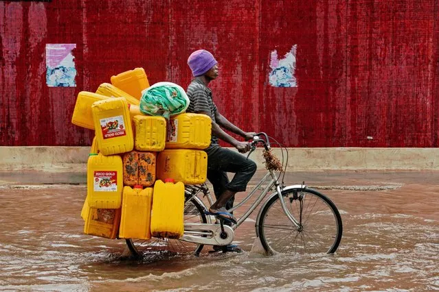 A man bicycles down a flooded street with empty cooking oil containers during a rain storm in Dar es Salaam, Tanzania on November 23, 2016. (Photo by Daniel Hayduk/AFP Photo)