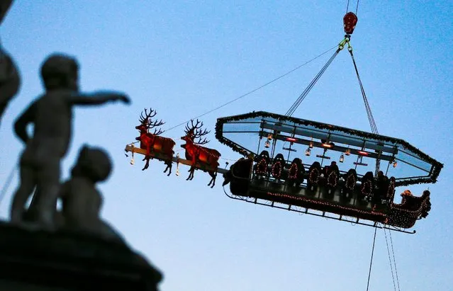 Guests enjoy dinner at the table “Santa in the sky”, lifted by a crane and decorated to match the appearance of a “Santa Sleigh” as part as the Christmas festivities, in Brussels, Belgium, November 25, 2016. (Photo by Yves Herman/Reuters)