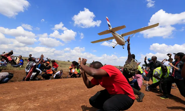 Spectators react as a plane flies over them during the Vintage Air Rally at the Nairobi national park in Kenya's capital Nairobi, November 27, 2016. (Photo by Thomas Mukoya/Reuters)