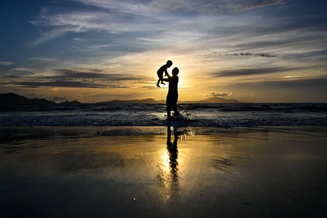 A man plays with his child at a beach at sunset in Banda Aceh on August 2, 2023. (Photo by Chaideer Mahyuddin/AFP Photo)