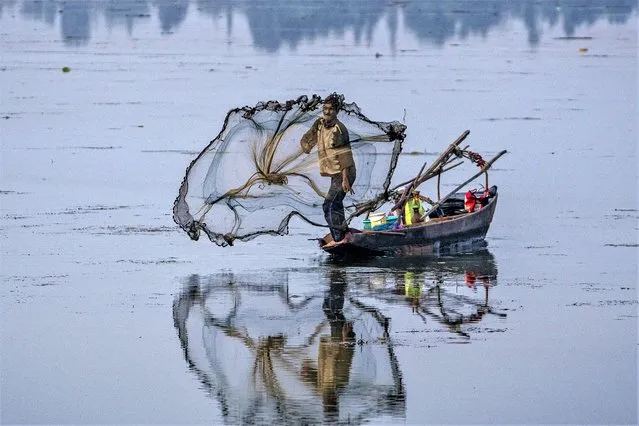 A Kashmiri fisherman casts his net into the waters of the Dal Lake on the outskirts of Srinagar, Indian controlled Kashmir, Tuesday, August 29, 2023. (Photo by Dar Yasin/AP Photo)