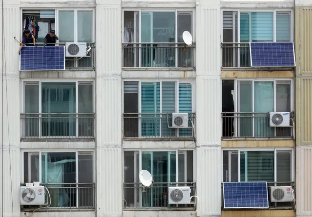 Workers install solar modules on apartment balconies in Seoul, South Korea, 20 June 2017. More and more people are getting interested in new and renewable energy in the country. (Photo by EPA/Yonhap)