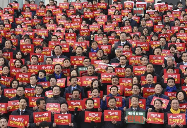 Lawmakers and members of opposition parties hold cards during a rally demanding the impeachment of South Korean President Park Geun-hye at the National Assembly in Seoul, South Korea, Wednesday, December 7, 2016. Park, who faces impeachment this week, rose to power with the support of conservatives enamored of the economic growth ushered in by her late dictator father decades ago. The sign read “President Park Geun-hye” and “Impeachment!”. (Photo by Ahn Young-joon/AP Photo)