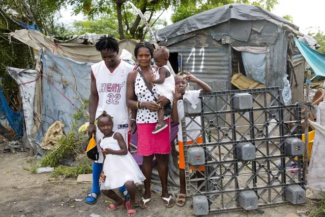 In this August 29, 2018 photo, Changlair Aristide stands with his wife Violene Mareus and children outside their home near the Truitier landfill where Aristide scavenges for valuables to use or sell in the Cite Soleil slum of Port-au-Prince, Haiti, before Aristide leaves to play soccer with a group of friends. Mareus said she hopes to move to a nice home one day in which she doesn't have to hold up tarps when it rains. (Photo by Dieu Nalio Chery/AP Photo)