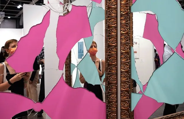 A visitor wearing a face mask takes a close look at an artwork “Two Less One coloured” created by Italian artist Michelangelo Pistoletto at Art Basel in Hong Kong Wednesday, May 19, 2021. (Photo by Vincent Yu/AP Photo)