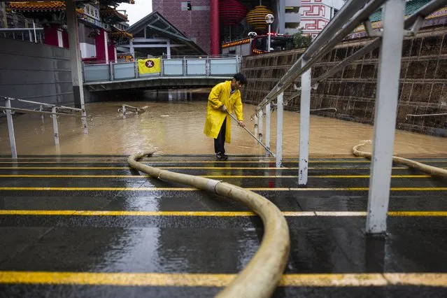 A worker clears water on a flooded street following heavy rainstorms in Hong Kong, Friday, September 8, 2023. Rain pouring onto Hong Kong and southern China overnight flooded city streets and some subway stations, halting transportation and forcing schools to close Friday. (Photo by Louise Delmotte/AP Photo)