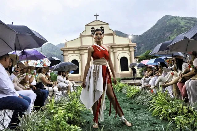 A model displays a creation by designers members of the Carabobo Sostenible program who present a collection made of corn cob husks, plastic, and paper in front of the facade of the Virgen del Carmen church in the town of Mariara, Carabobo state, Venezuela, on August 3, 2023. (Photo by Juan Carlos Hernandez/AFP Photo)