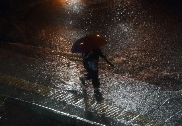 A woman holds an umbrella while walking under rainfall in Basaksehir district of Istanbul, Turkey, Tuesday, September 5, 2023. Flash floods triggered by heavy rains swept through a campsite in northwest Turkey on Tuesday, killing at least two people, officials said. Four other people were reported missing. (Phoot by Khalil Hamra/AP Photo)