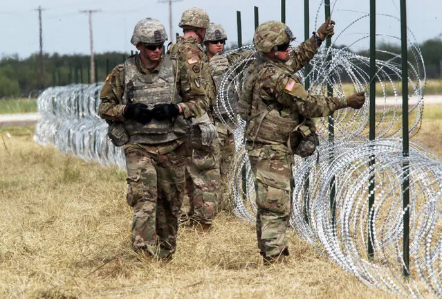 U.S. Army soldiers from Ft. Riley, Kansas, put up barbed wire fence for an encampment to be used by the military near the U.S. Mexico border in Donna, Texas, U.S., November 4, 2018. (Photo by Delcia Lopez/Reuters)
