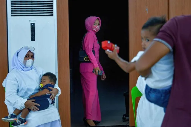 A health worker calms a child administer with the Sinovac vaccine against Covid-19 coronavirus during a mass vaccination at a convention hall building in Banda Aceh on June 7, 2021. (Photo by Chaideer Mahyuddin/AFP Photo)