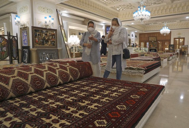 Customers look at rugs at a hand crafts store at Iran Mall shopping center in Tehran, Iran, Wednesday, June 9, 2021. The West considers Iran's nuclear program and Mideast tensions as the most important issues facing Tehran, but those living in the Islamic Republic repeatedly point to the economy as the major issue facing it ahead of its June 18 presidential election. (Photo by Vahid Salemi/AP Photo)