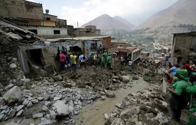 People remove mud and rocks after a massive landslide in Chosica, March 24, 2015. (Photo by Mariana Bazo/Reuters)