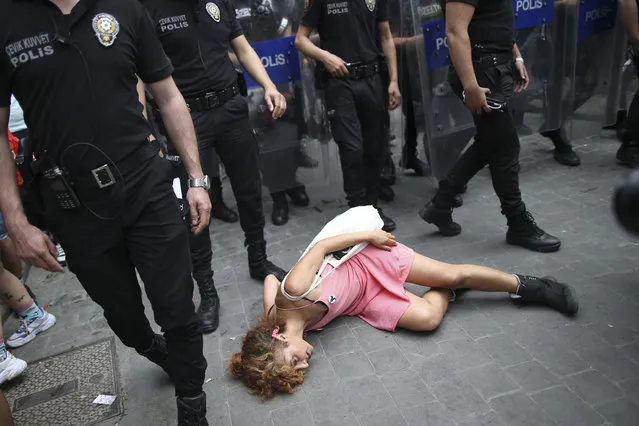 A protester performs a dance act as police walk to disperse a pride rally in central Istanbul, Saturday, June 26, 2021. Police used tear gas to disperse the crowds and detained dozens of LGTBI activists as hundreds defied a ban and tried to stage a gay pride event. (Photo by Emrah Gurel/AP Photo)