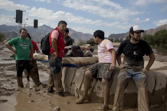 Men stand beside a woman rescued from the mud as she rests on a mattress in Copiapo, Chile, Thursday, March 26, 2015. (Photo by Pablo Sanhueza/AP Photo)