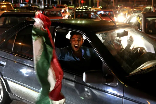 An Iranian waves his country's flag while celebrating on a street in northern Tehran, Iran, Thursday, April 2, 2015, after Iran's nuclear agreement with world powers in Lausanne, Switzerland. (Photo by Ebrahim Noroozi/AP Photo)