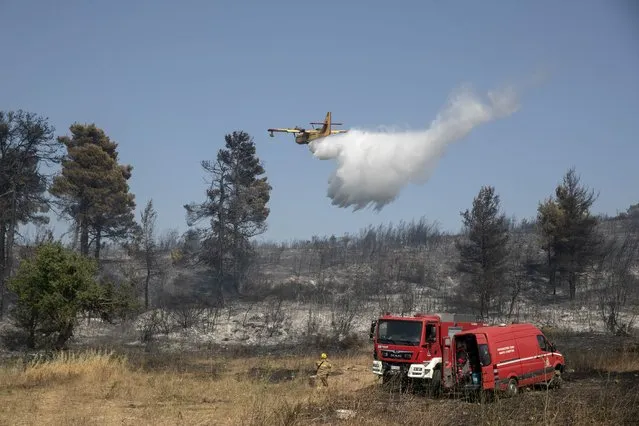 A firefighting airplane drops water during a forest fire at Dionysos northern suburb of Athens, on Tuesday, July 27, 2021. Greek authorities have evacuated several areas north of Athens as a wildfire swept through a hillside forest and threatened homes despite a large operation mounted by firefighters. (Photo by Yorgos Karahalis/AP Photo)