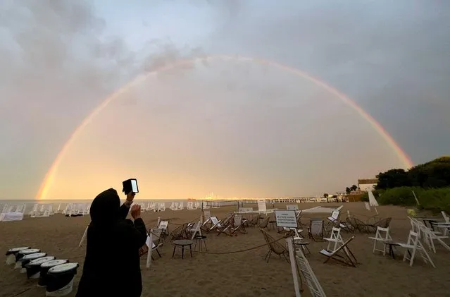 A woman takes picture of the rainbow after heavy rain in Sopot, Poland on July 24, 2023. (Photo by Kacper Pempel/Reuters)