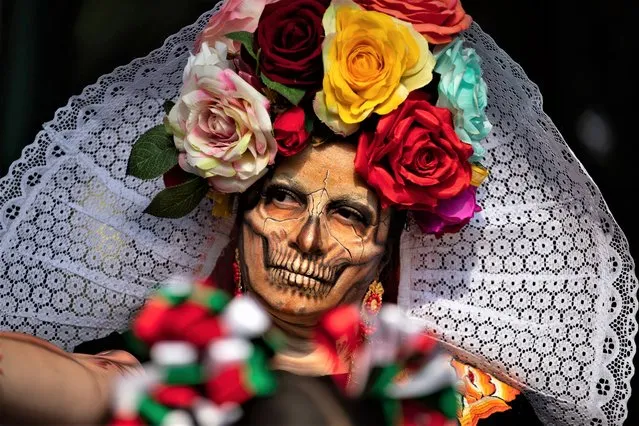 A woman dressed as a “Catrina” takes part in the Procession of Catrinas, at Reforma Avenue, in Mexico City, Mexico on October 23, 2022. The elegant figures of skeletons better known as Catrinas were created as satirical prints by Mexican artist Jose Guadalupe Posada in 1910, La Catrina is an iconic symbol of the Day of the Dead celebrations. (Photo by Daniel Cardenas/Anadolu Agency via Getty Images)