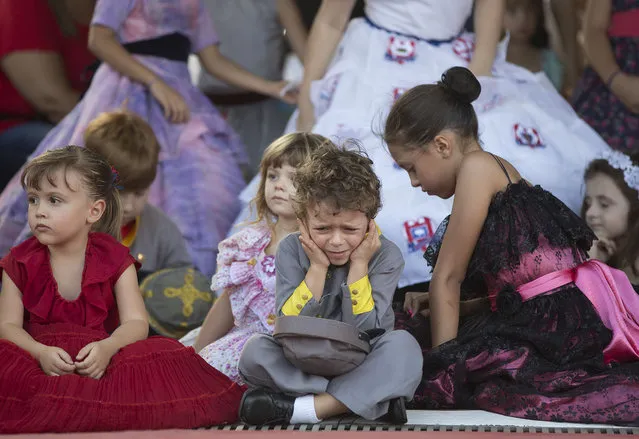 A child wearing Confederate-era uniform covers his ears from the noise during a party to celebrate the 150th anniversary of the end of the American Civil War in Santa Barbara d'Oeste, Brazil, Sunday, April 26, 2015. (Photo by Andre Penner/AP Photo)