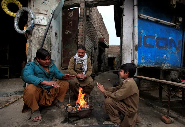 Men warm themselves by a fire to escape the cold on the outskirts of Islamabad, Pakistan January 17, 2017. (Photo by Faisal Mahmood/Reuters)