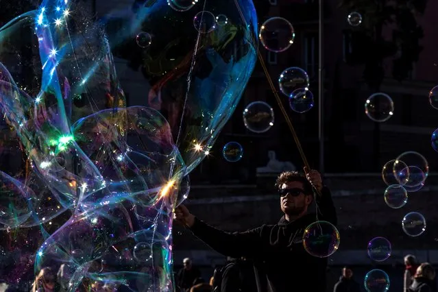 A man blows giant soap bubbles for tourists on Piazza del Popolo in downtown Rome on December 18, 2018. (Photo by Laurent Emmanuel/AFP Photo)