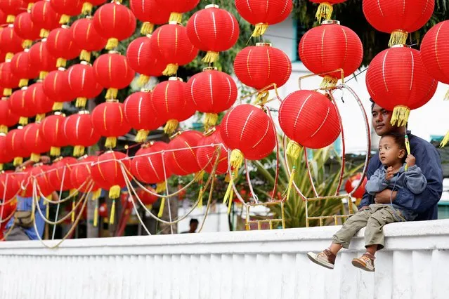 A man holds his son near red lanterns during the Lunar New Year's Eve in Surakarta, Central Java province, Indonesia on February 9, 2024. (Photo by Willy Kurniawan/Reuters)