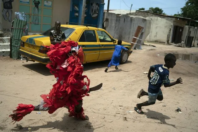A boy dressed up as a Kankurang play chases a child in Serrekunda, Gambia, Friday, September 24, 2021. (Photo by Leo Correa/AP Photo)