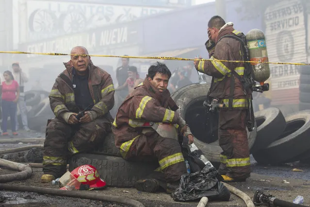 Firemen rest after working to control a fire at a tire warehouse in La Terminal, the largest and most important market in Guatemala City, Wednesday, May 6, 2015. (Photo by Moises Castillo/AP Photo)