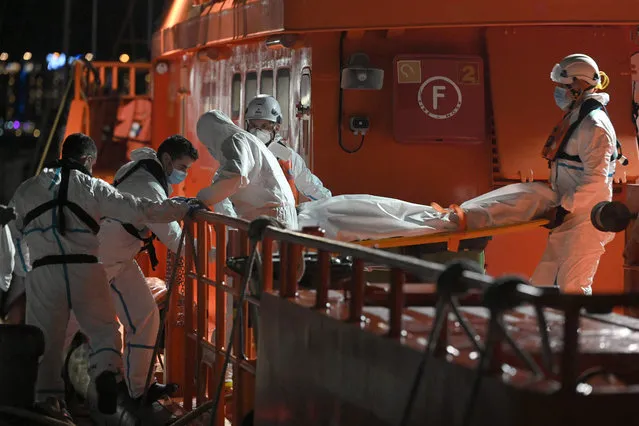 Emergency personnel disembark the body of a deceased migrant in the port of Arguineguin, after their rescue at the coast of the Canary island of Gran Canaria, Spain, on November 18, 2021. Migrant crossings from North Africa into Spain have surged this year, with many people risking their lives on dangerous boat journeys across the Mediterranean. Some 16,827 migrants have arrived in the Canaries between January and October, an increase of 44 percent from the same period a year ago, according to Spain's interior ministry. (Photo by Lluis Gene/AFP Photo)
