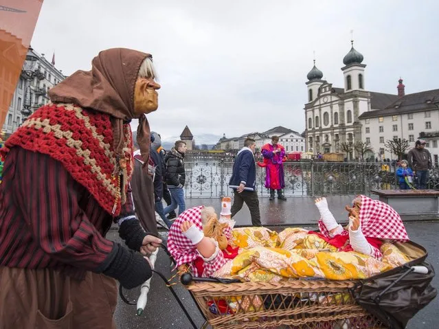 A participant pushes a pram with dolls as he walks on the streets of Lucerne. (Photo by Sigi Tischler/Keystone)