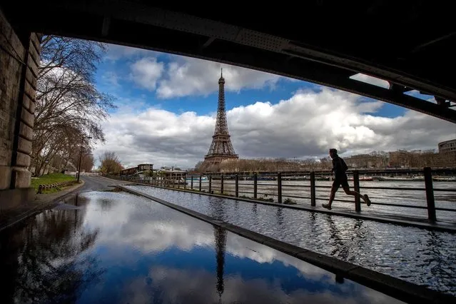 A man jogs on the flooded Seine river banks with the Eiffel Tower appearing in the background in Paris on March 5, 2024. (Photo by Guillaume Baptiste/AFP Photo)
